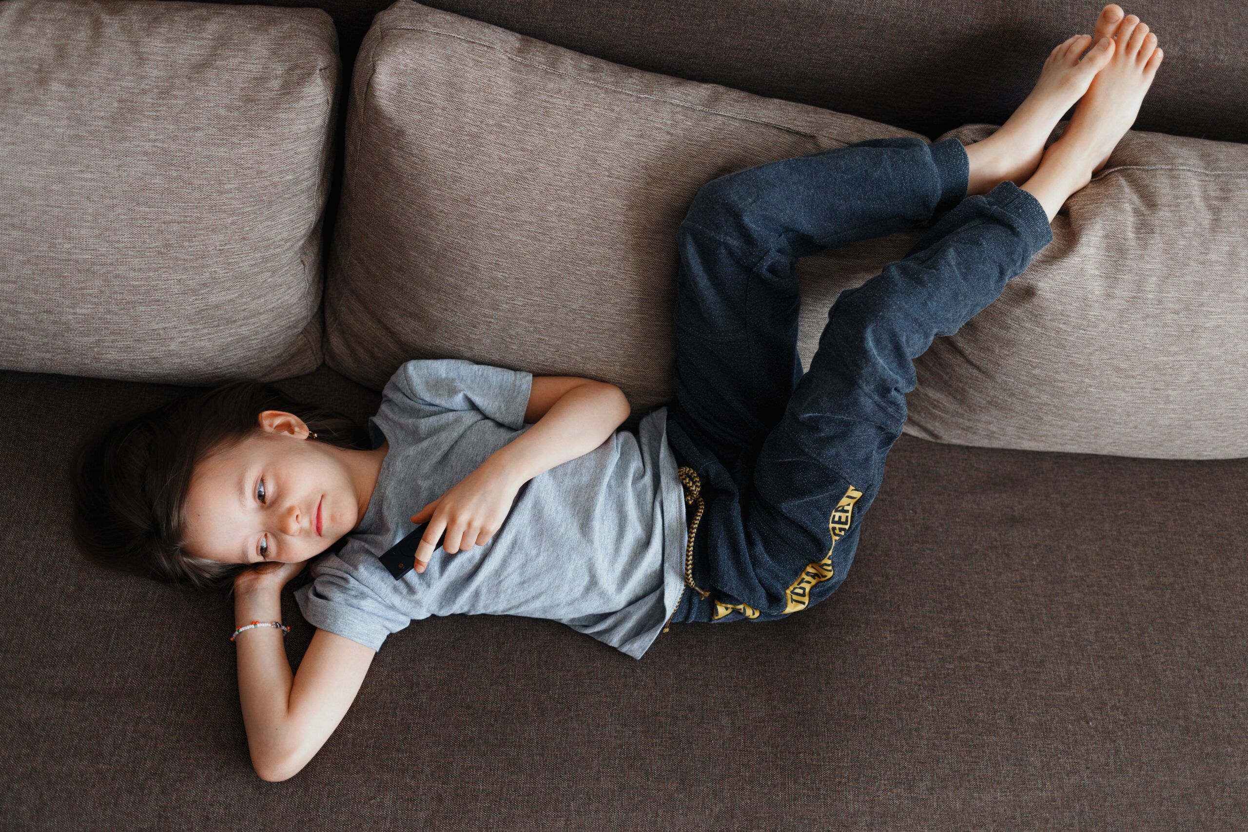 Child sitting alone outdoors looking thoughtful with no screens or toys nearby