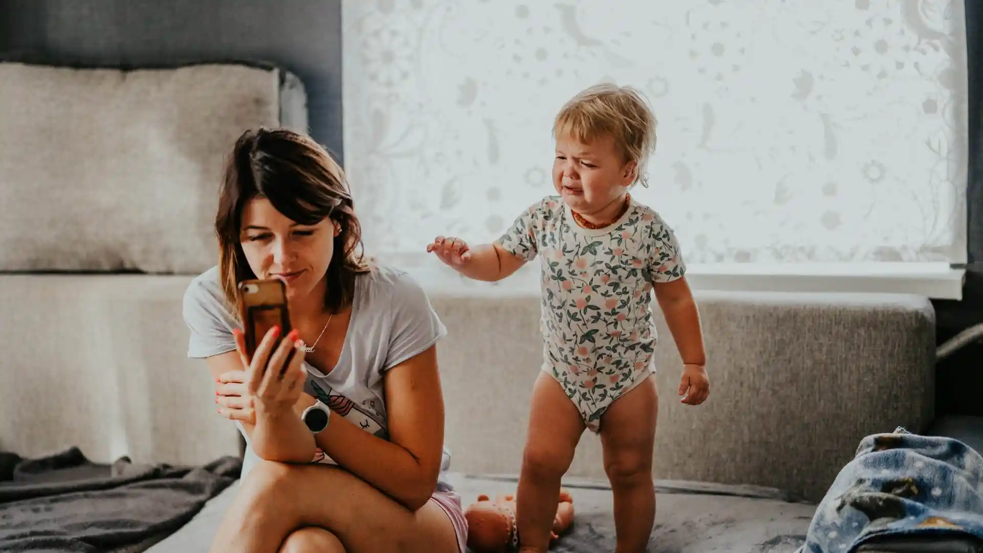 Parent searching Chelsea Acton's famous parenting tips on phone late at night, looking confused by conflicting bios