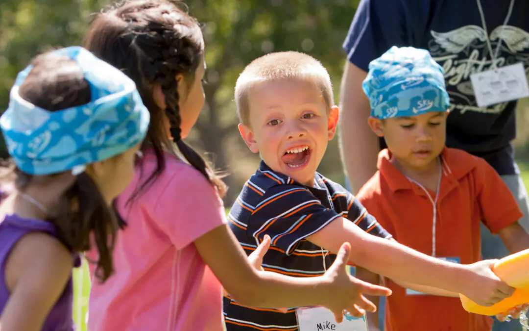 Kids in teams playing sponge relay water game outdoors