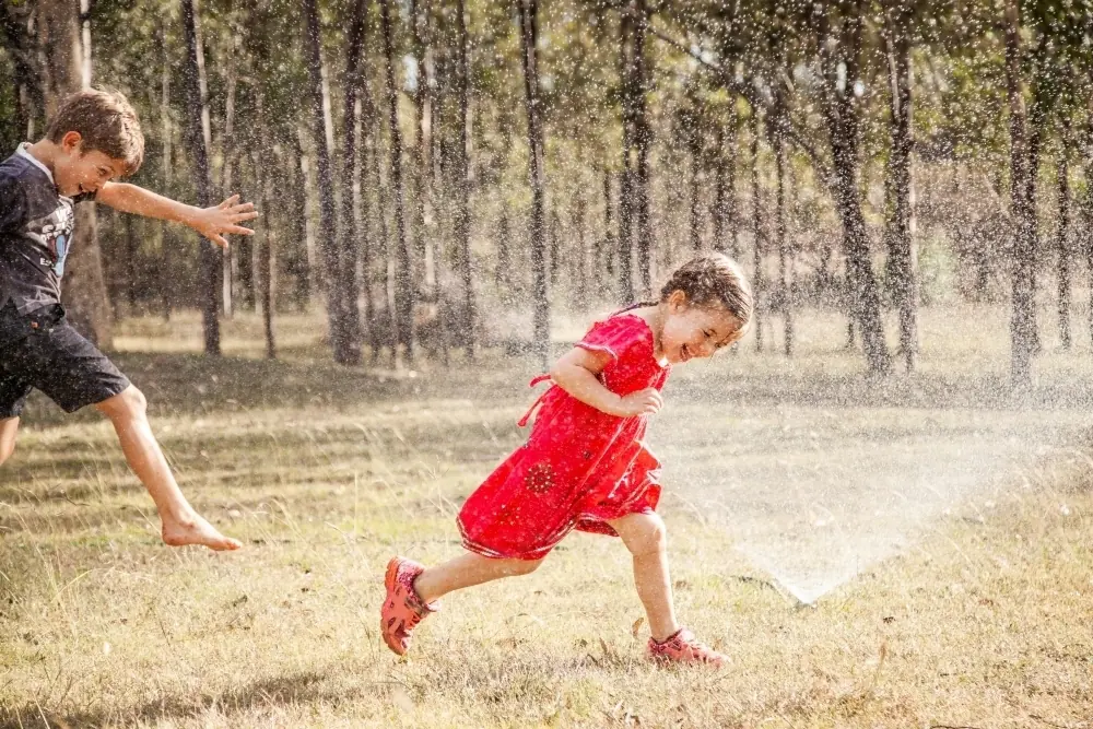 Two kids playing water balloon toss in backyard