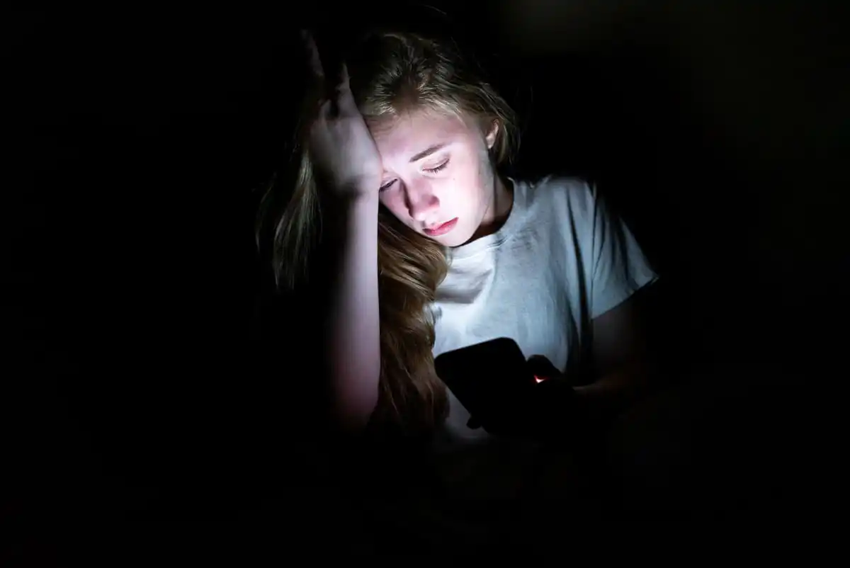 Teenager looking anxious while checking phone notifications, illustrating signs of cyberbullying parents might miss