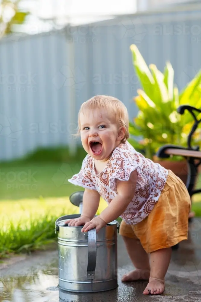 Toddler fishing toys out of kiddie pool with toes