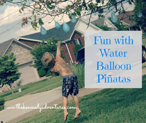 Kids taking turns swinging at hanging water balloon piñata