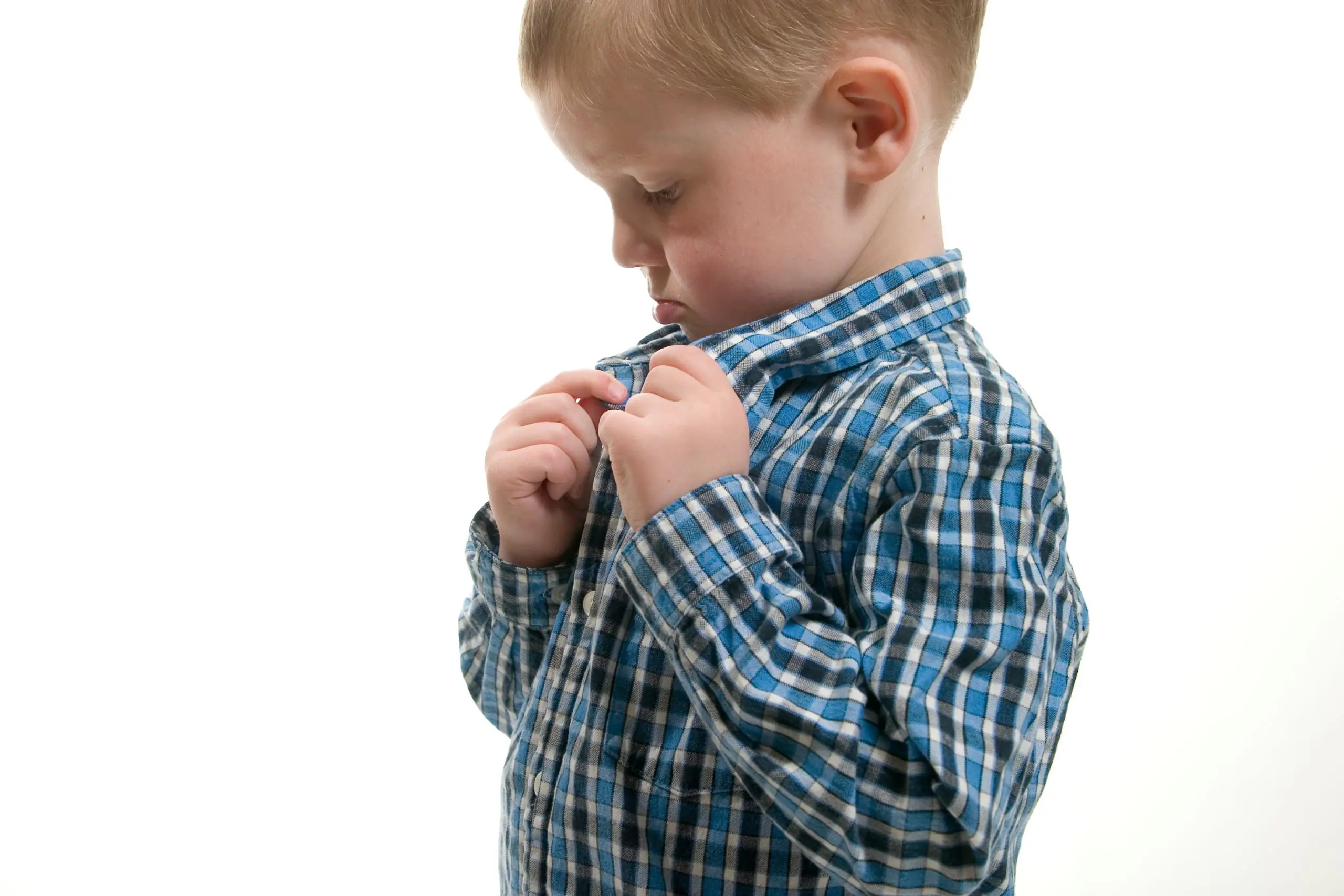 Child attempting to button a shirt, fasteners difficulty order from Velcro to laces